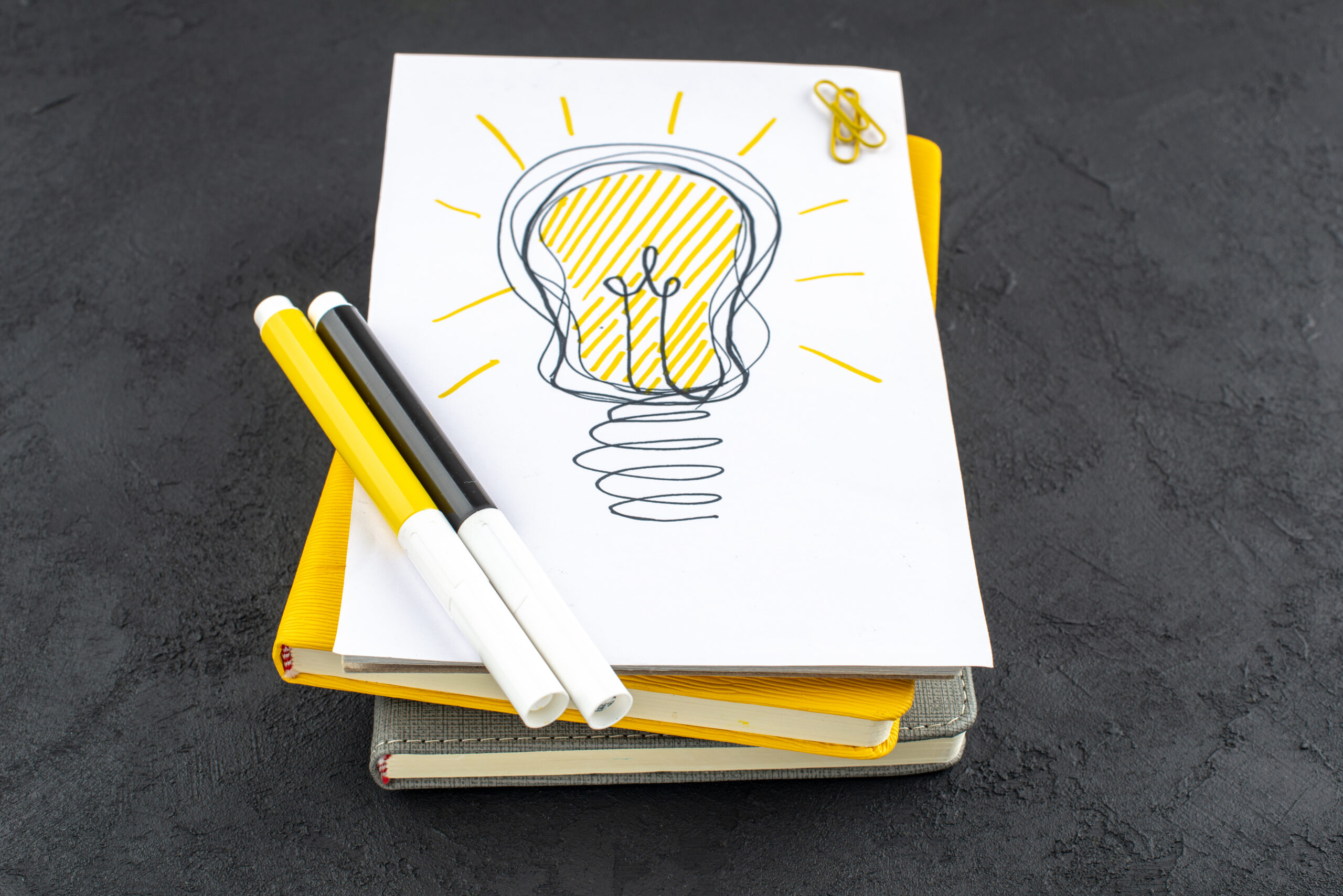 Creative ideas represented by a light bulb, notepad, and design tools